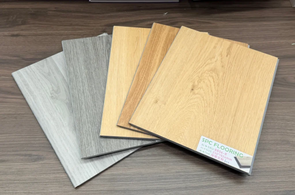 SPC flooring sample boards used to compare wood-grain shades and finishes before bulk ordering.